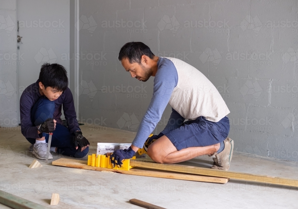 A father teaching his son how to safely use a manual saw - Australian Stock Image