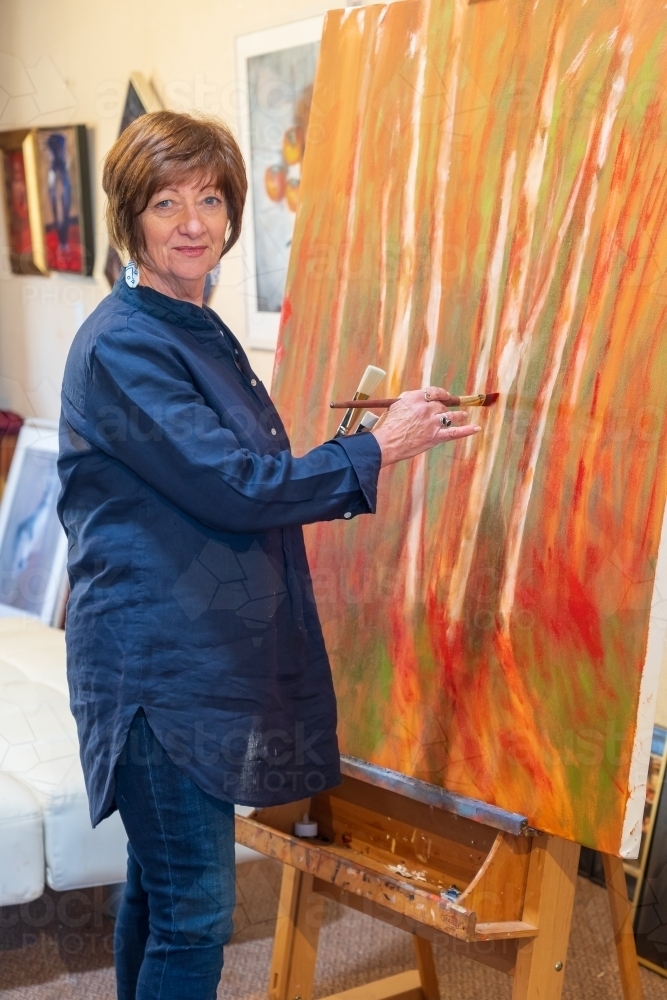 A female artist painting a large colourful canvas - Australian Stock Image