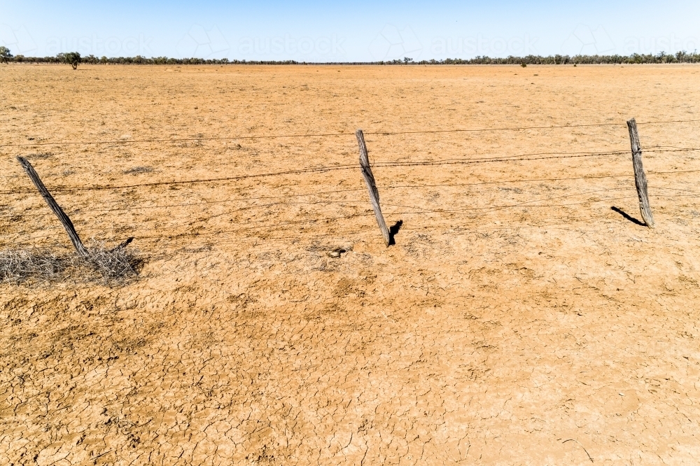 A fence and dusty paddock in drought affected Queensland. - Australian Stock Image