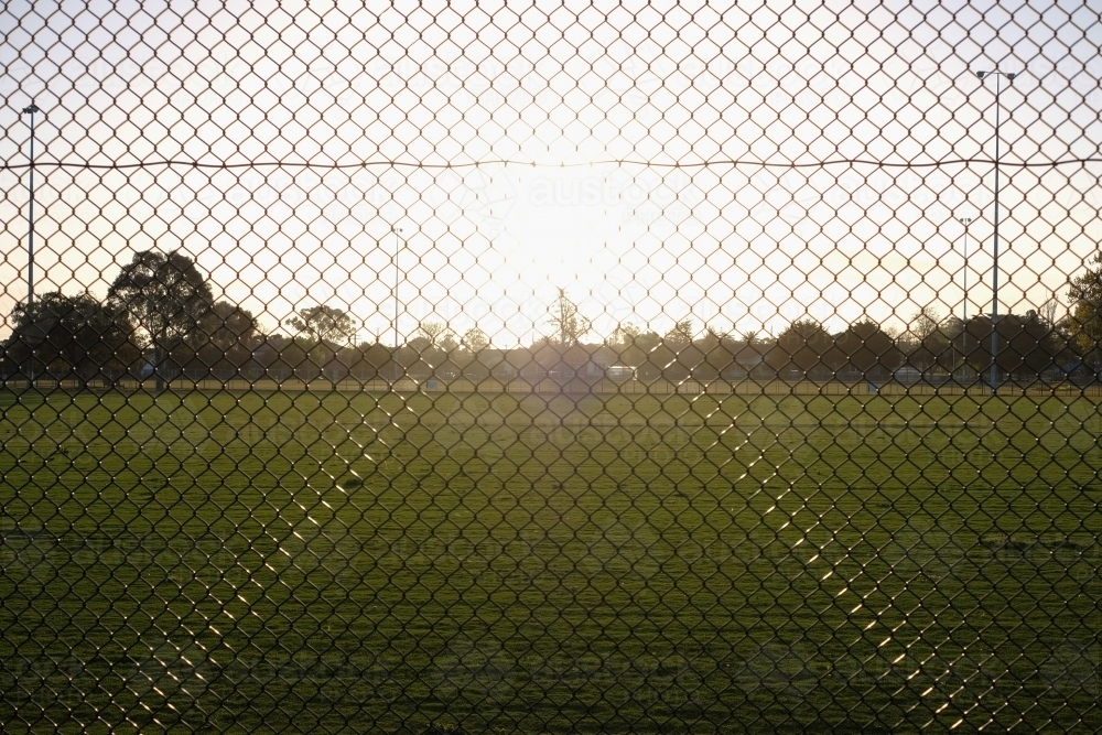 A fence around a sports field at sunrise - Australian Stock Image