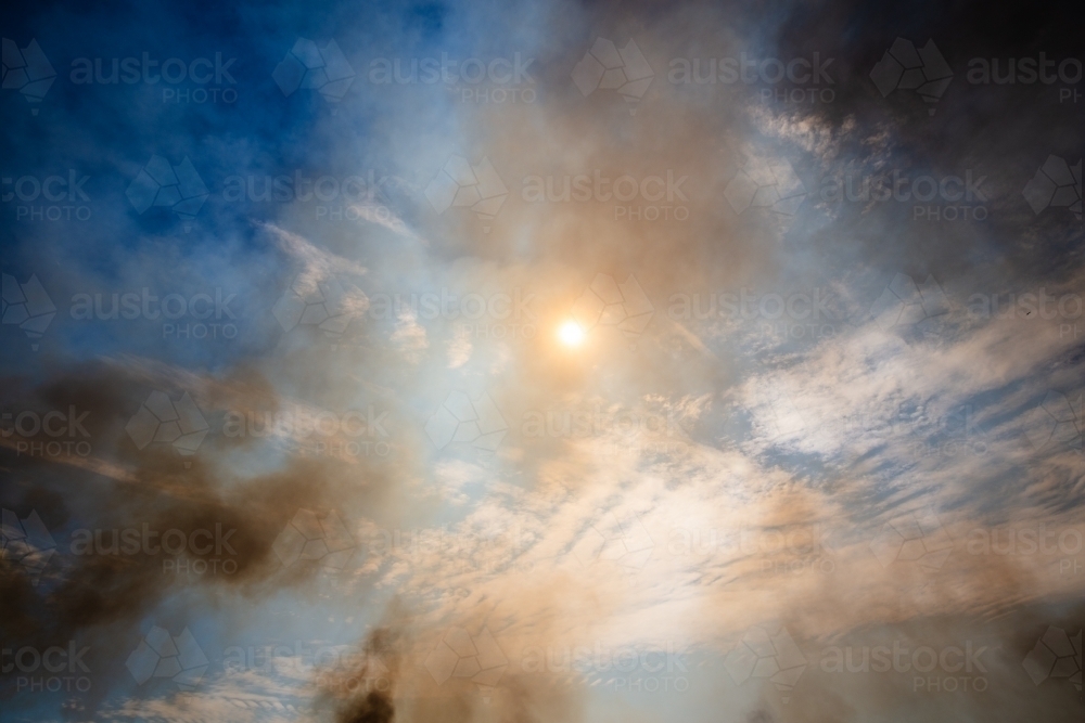 A few small fires making smoke in the sky caused by buring off. Central Australia. - Australian Stock Image
