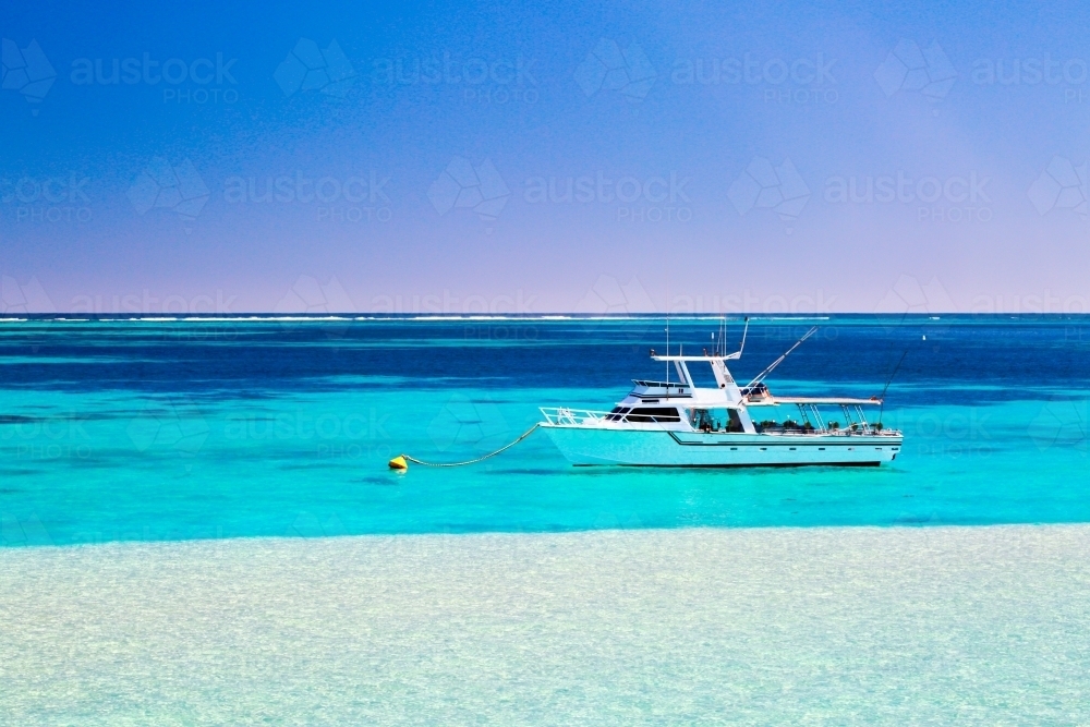 A fishing and diving tour boat on a mooring behind Ningaloo Reef - Australian Stock Image