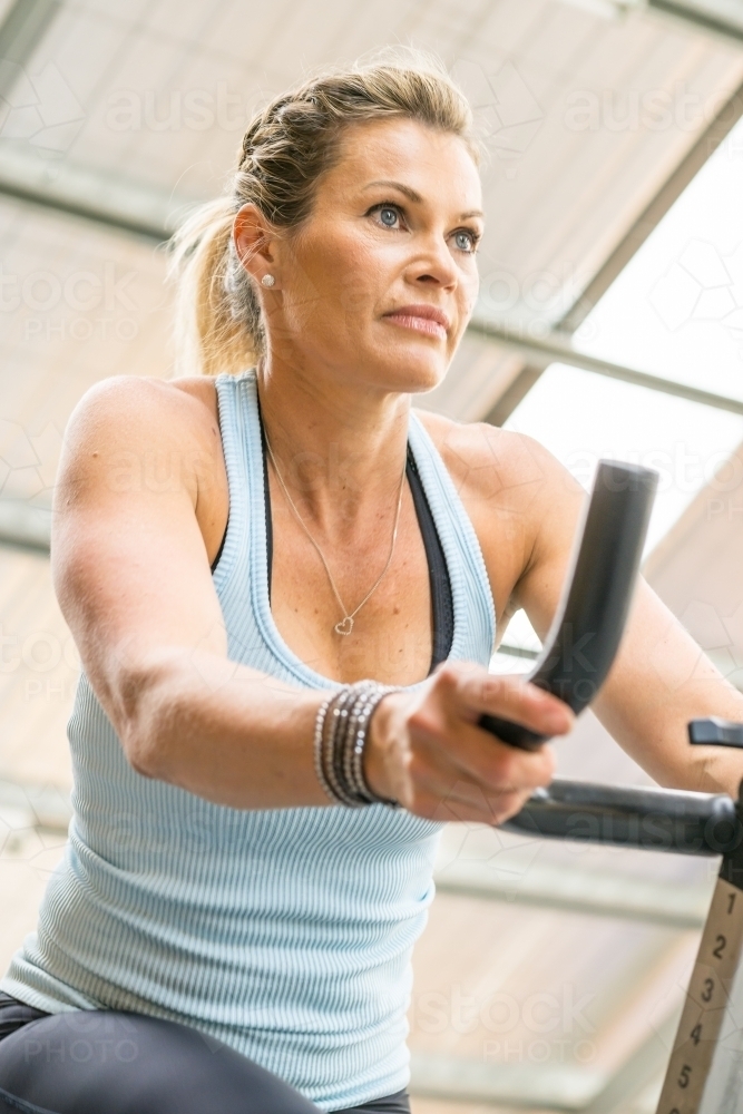 A fit woman riding an exercise bike in a gym - Australian Stock Image
