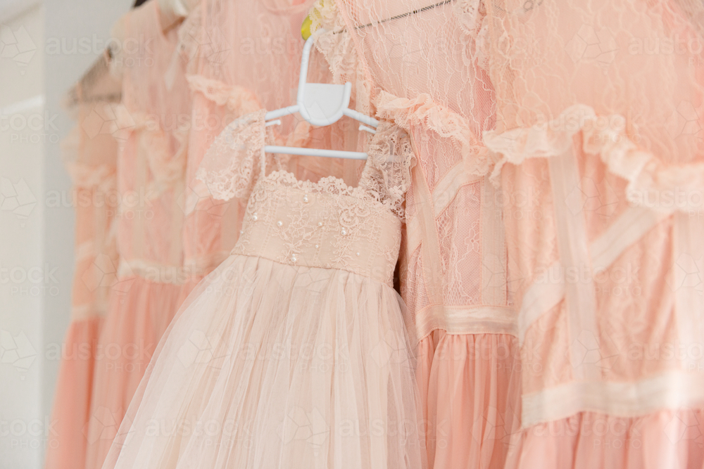 a flower girl dress hanging up with bridesmaid dresses - Australian Stock Image