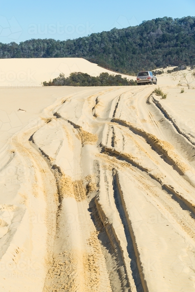 A four wheel drive leaving tracks in sand dunes - Australian Stock Image