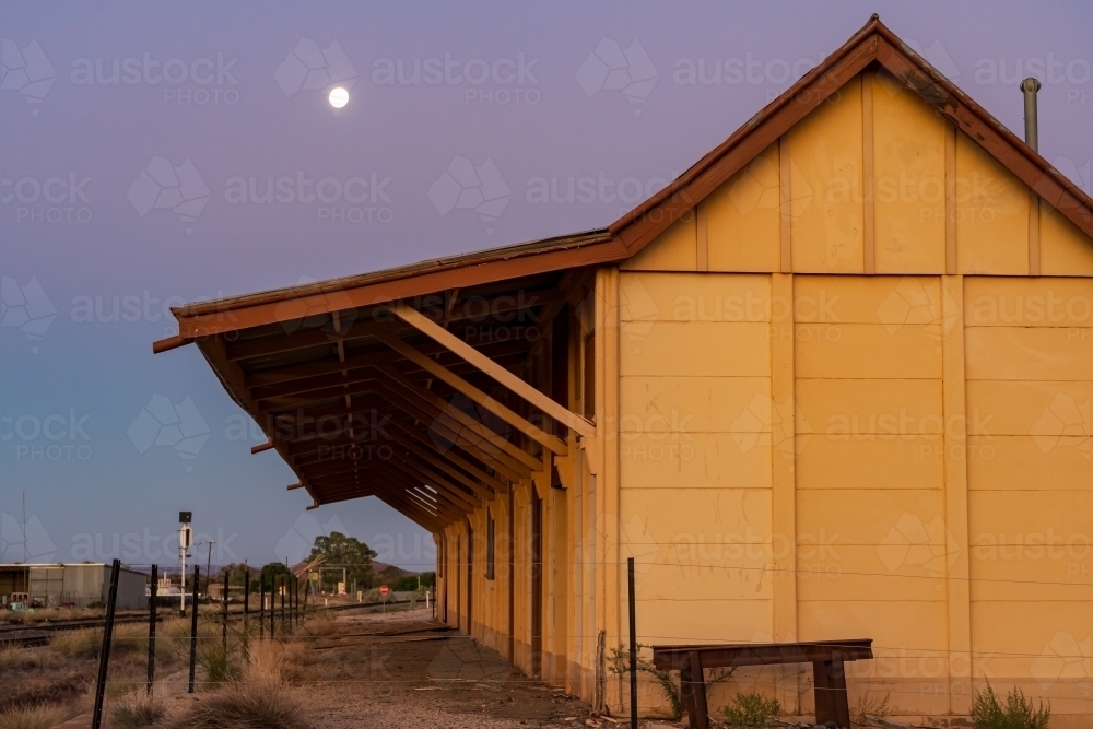 A full moon rising at twilight over an abandoned railway station - Australian Stock Image