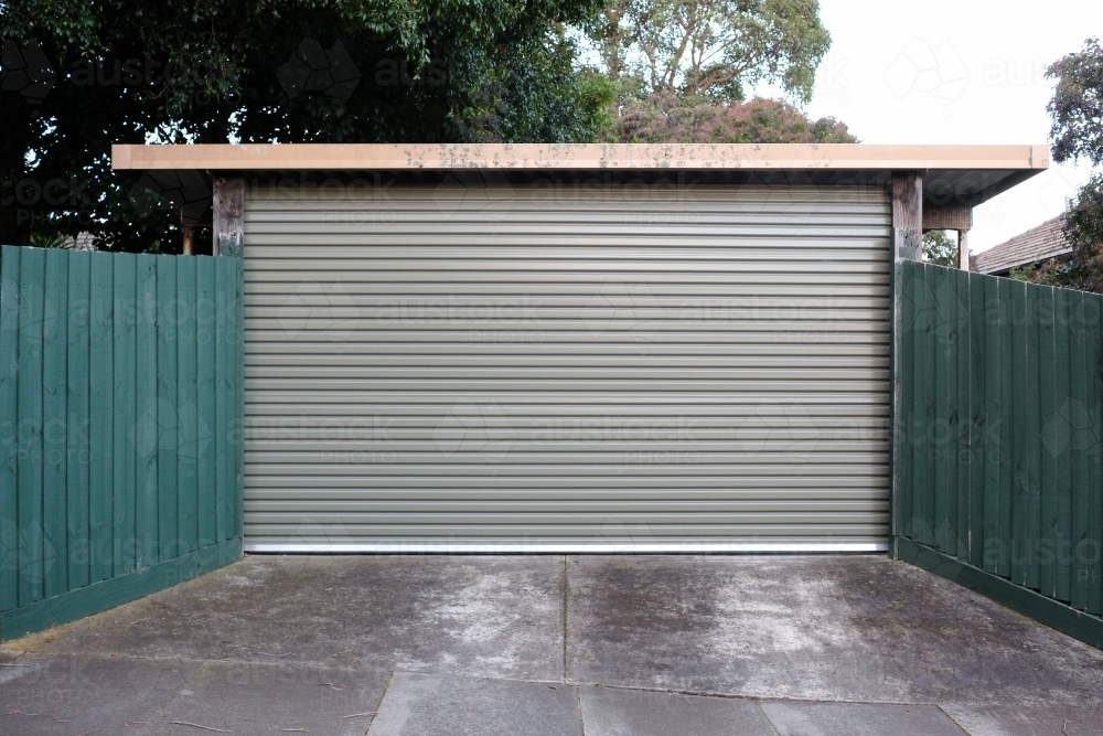 A garage roller door in between green fences - Australian Stock Image