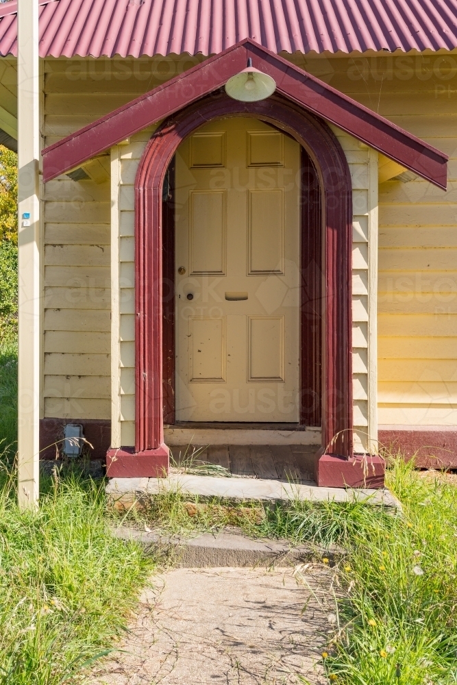 A garden path leading up to wooden door under an arched portico - Australian Stock Image