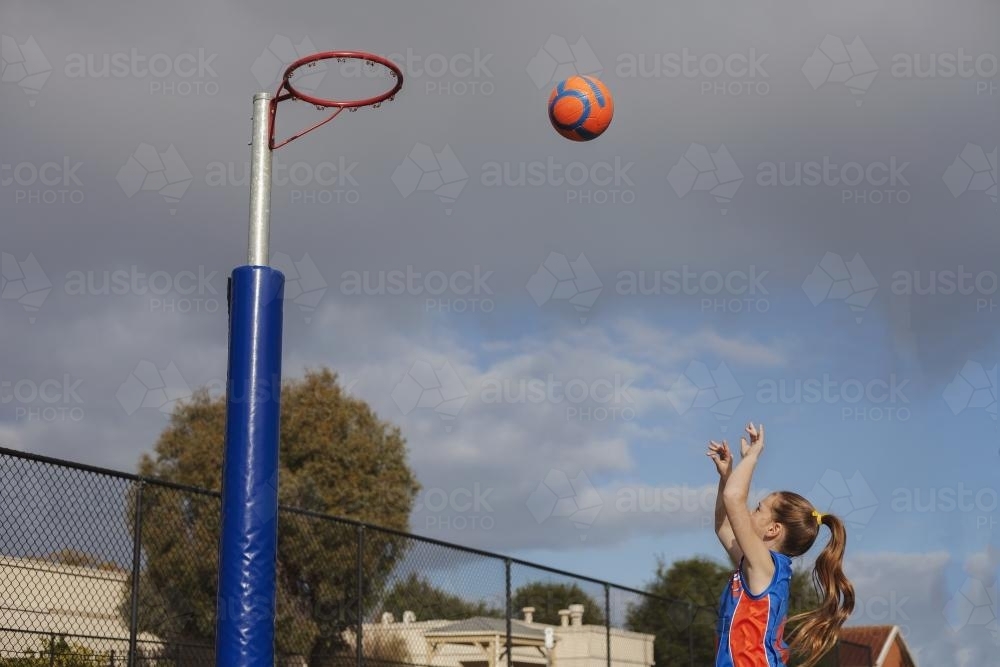 A girl playing Saturday morning netball throwing the ball - Australian Stock Image