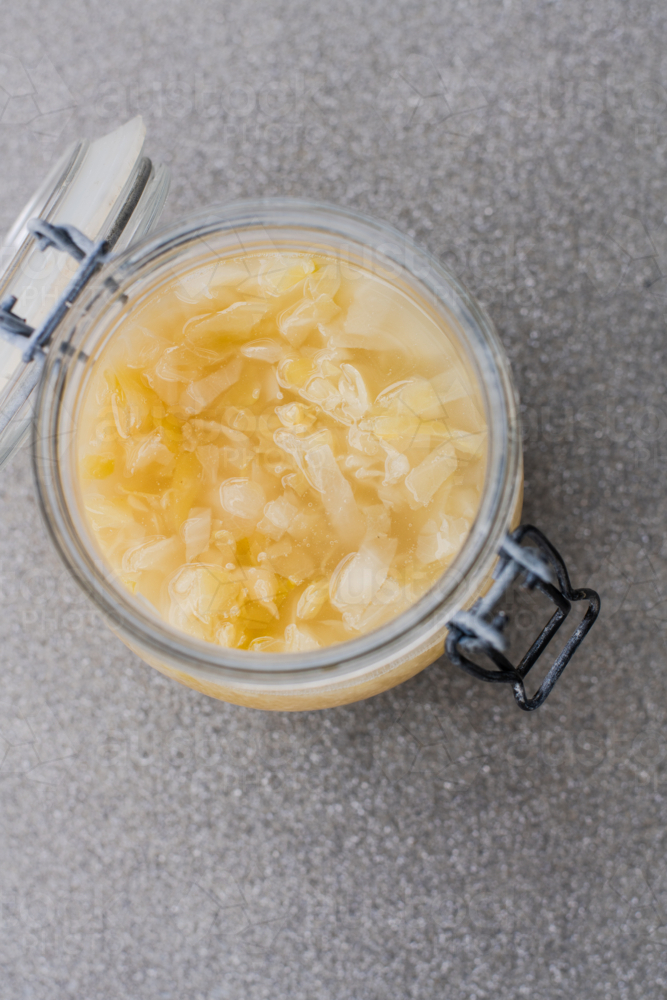 a glass jar has fermenting sauerkraut, day 10, bubbles on visible on the surface - Australian Stock Image