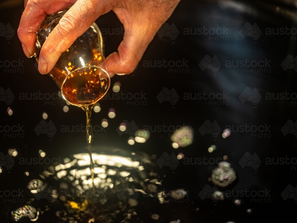 A glass of whisky poured into a whisky still - Australian Stock Image