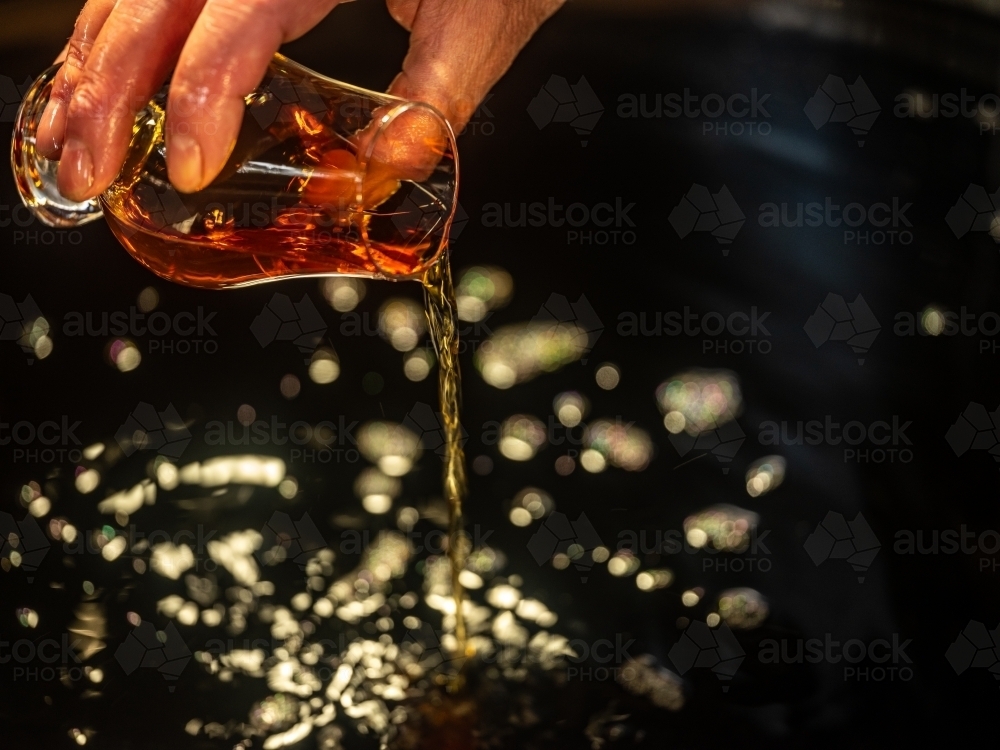 A glass of whisky poured into a whisky still - Australian Stock Image
