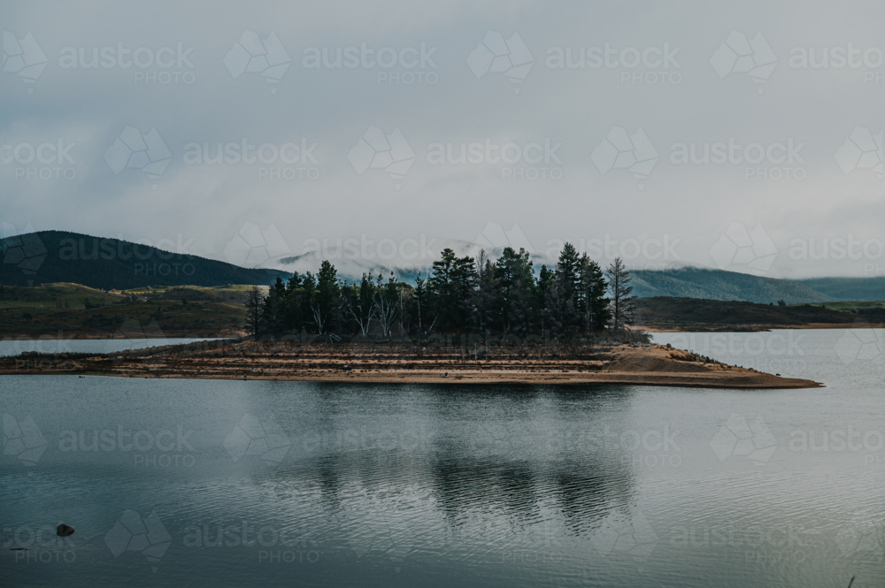 a glassy lake during draught on a winter day during a cloudy and fog weather - Australian Stock Image