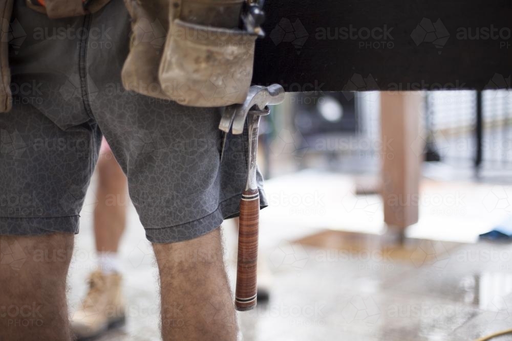 A hammer sits in a tradesman's belt. - Australian Stock Image