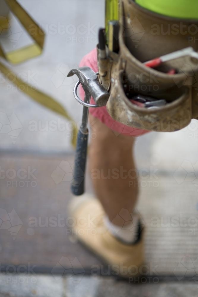 A hammer sits in a tradesman's belt. - Australian Stock Image