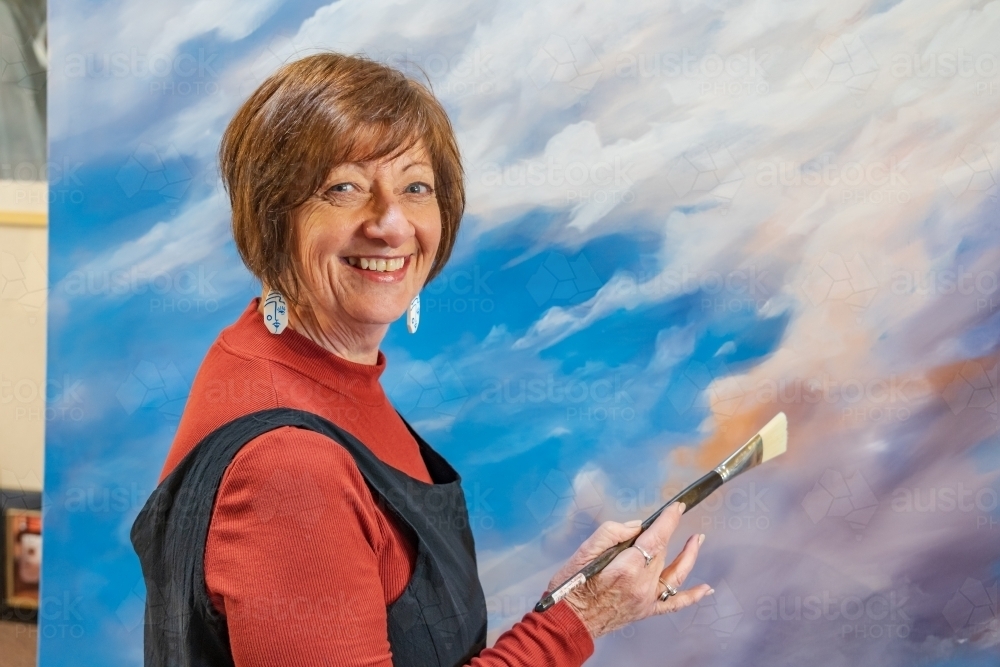 Image of A happy female artist standing in front of a colourful ...