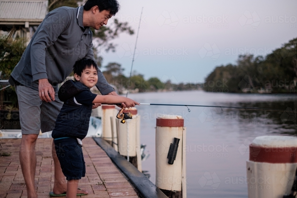 a happy kid being taught how to fish - Australian Stock Image