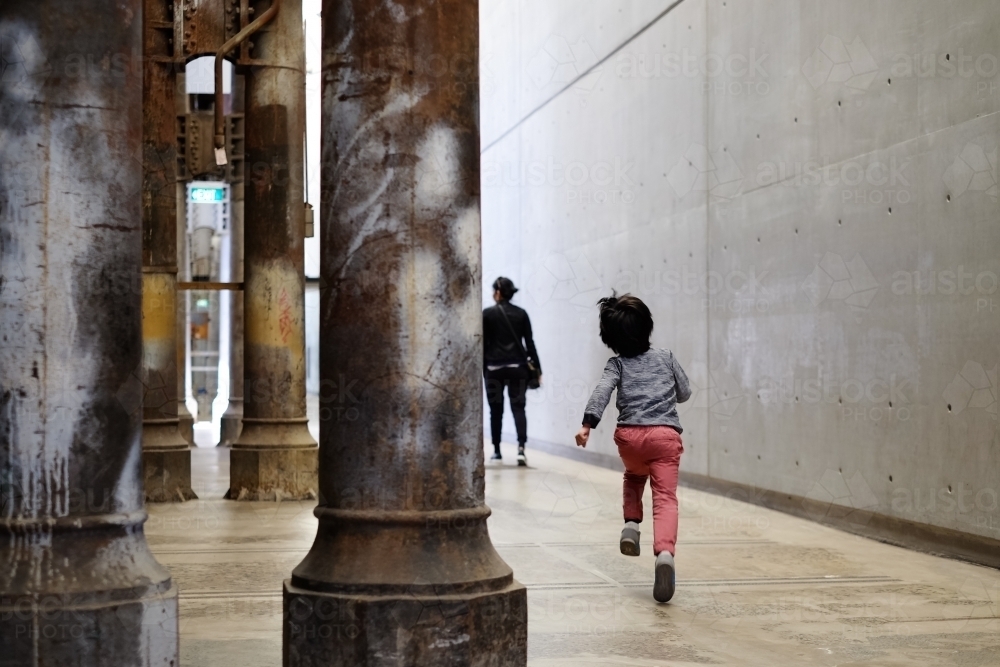 a happy kid, skipping, and running to mum in an industrial space - Australian Stock Image