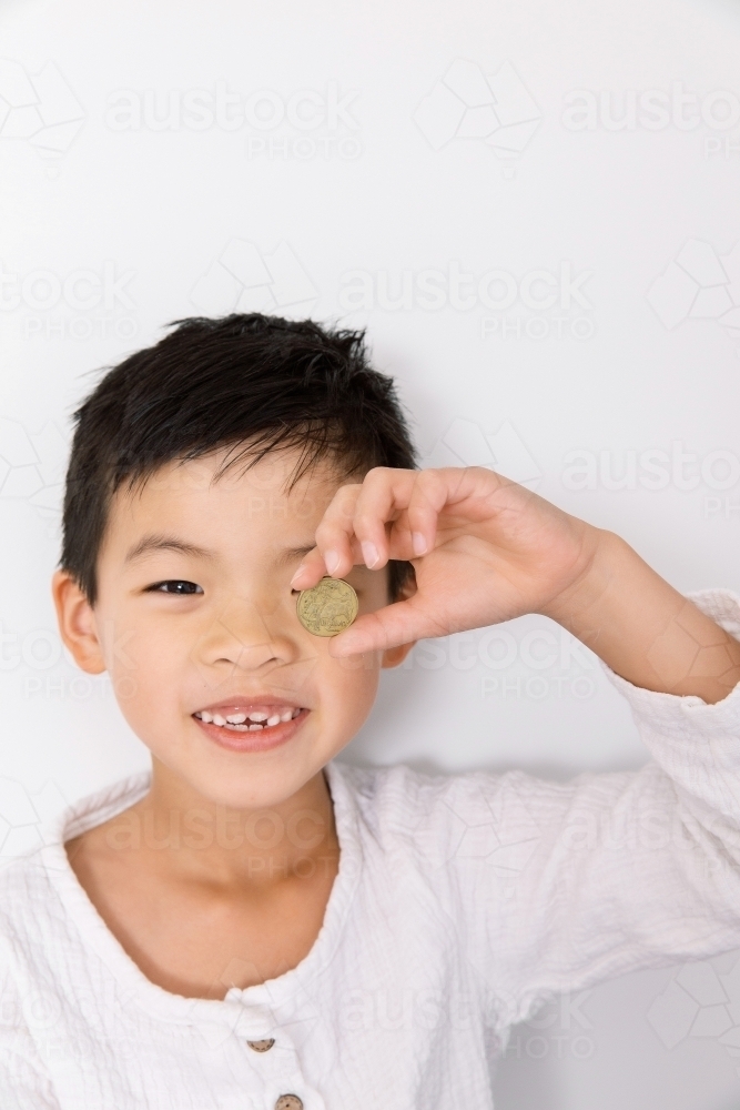 A happy young asian boy holding an australian coin - Australian Stock Image