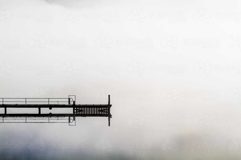 A jetty floats into the middle of a misty Huon River - Australian Stock Image
