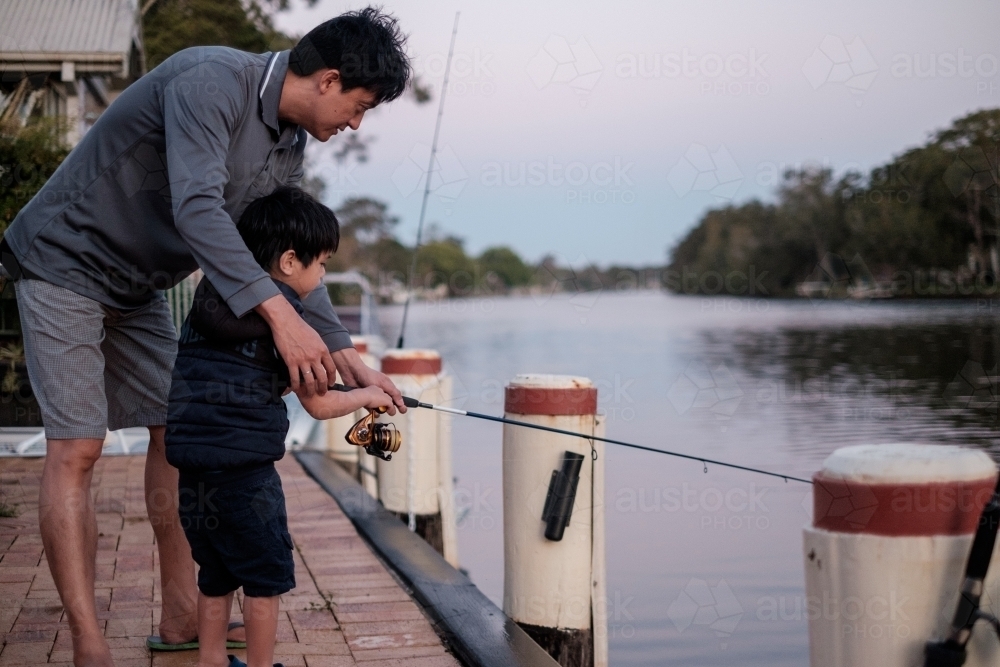a kid being taught how to fish - Australian Stock Image