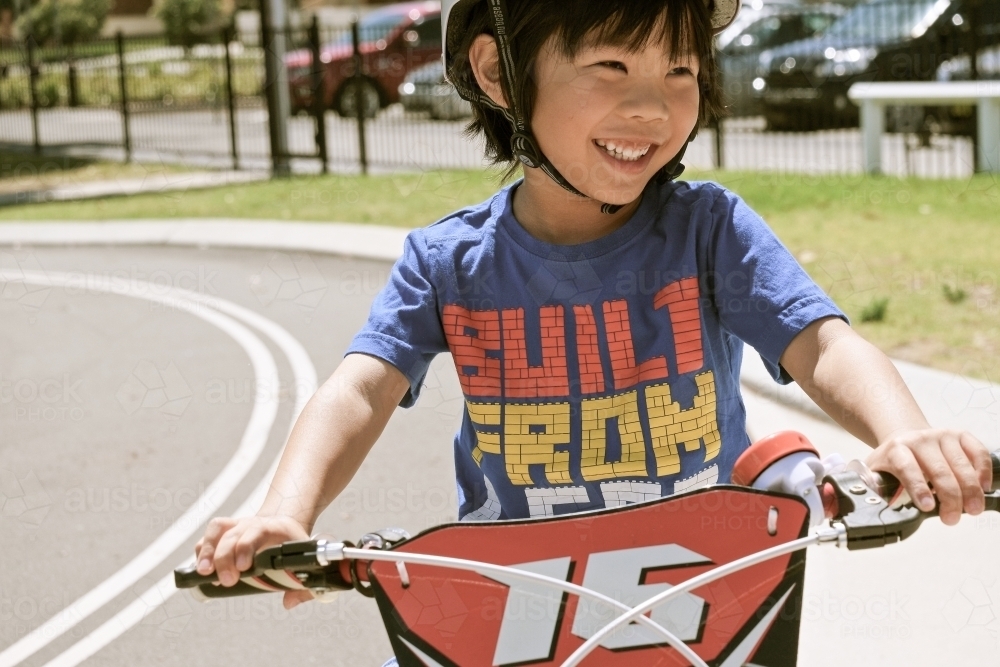 a kid happily riding his bike at the park - Australian Stock Image