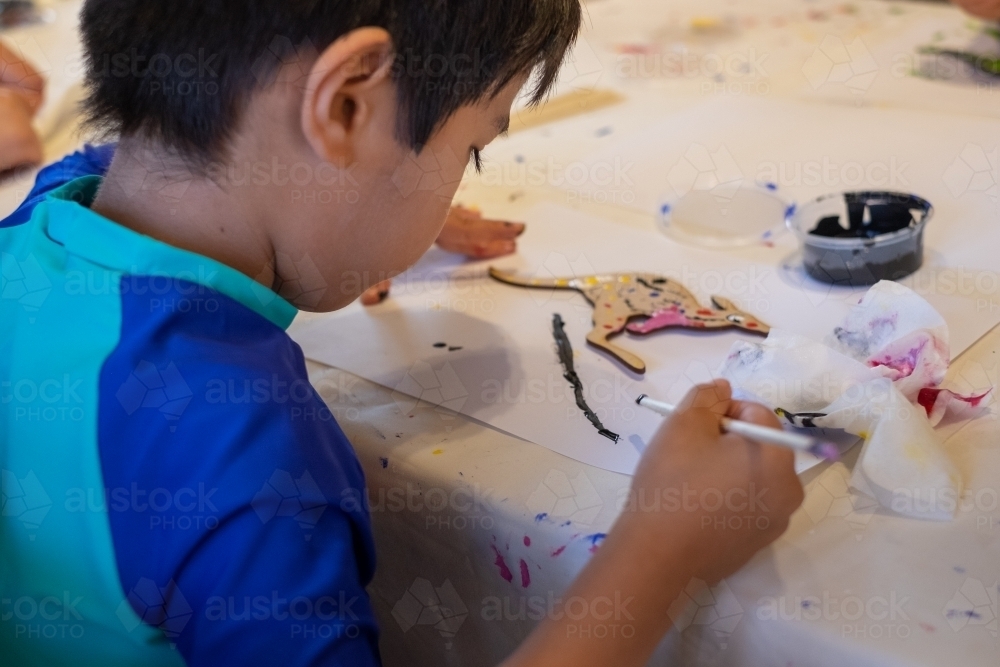 a kid painting a kangaroo in aboriginal styling - Australian Stock Image