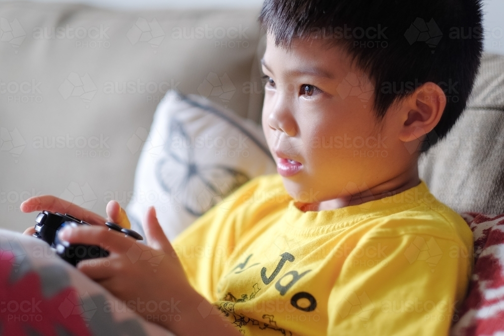 a kid, playing a console game in the living room - Australian Stock Image