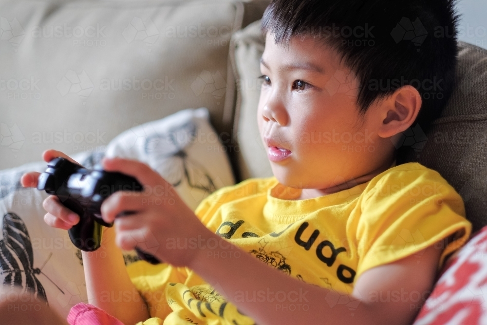 a kid, playing a console game in the living room - Australian Stock Image