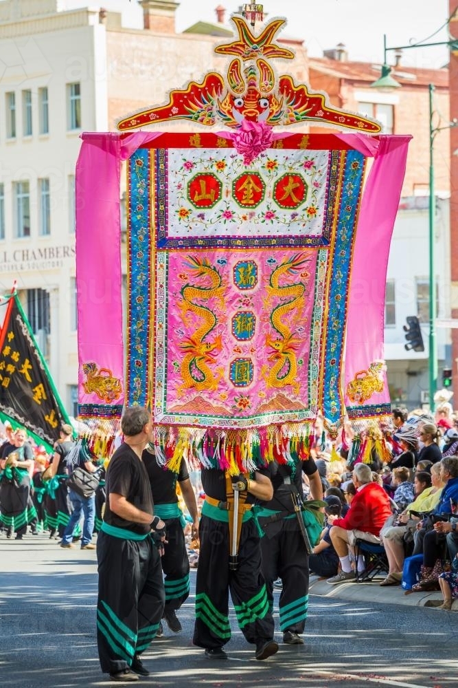 A large Chinese banner being carried in a parade - Australian Stock Image