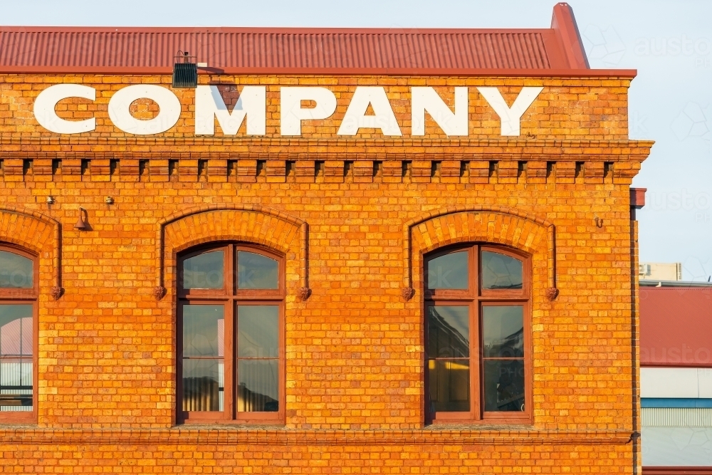 A large company sign above the windows of a red brick warehouse - Australian Stock Image
