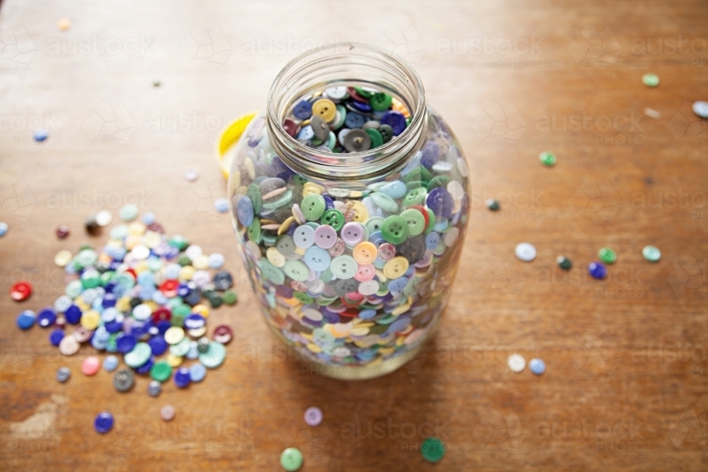 A Large jar of buttons sitting on a wooden table - Australian Stock Image
