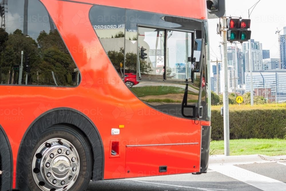 A large red bus waits at traffic lights - Australian Stock Image