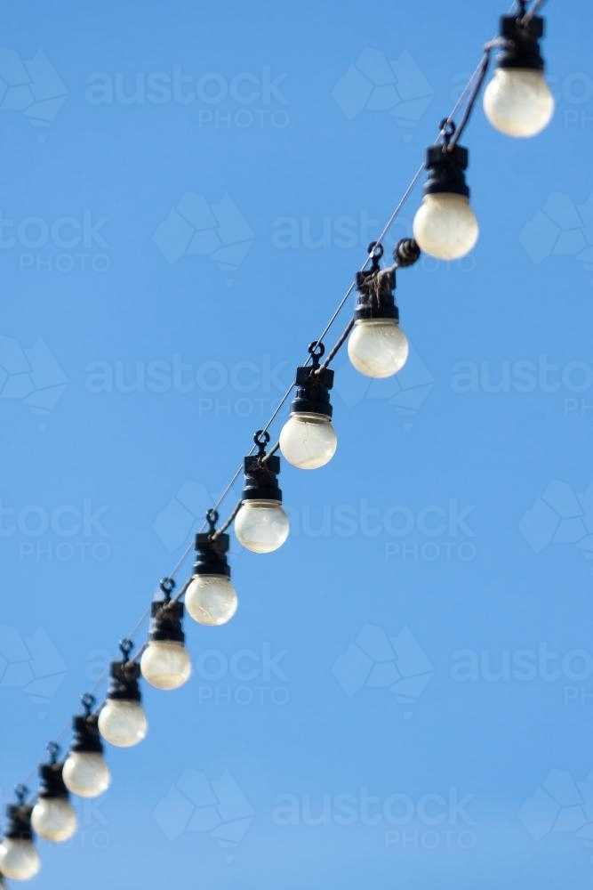 Image of A line of light bulbs hanging in a row Austockphoto