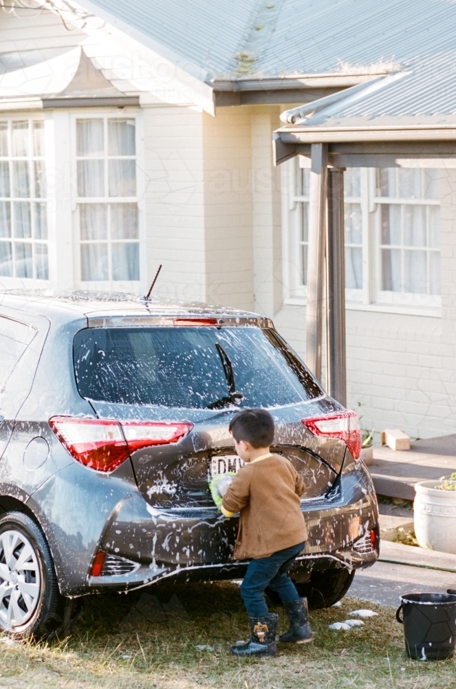 A Little Boy Washing Car in the Front Porch - Australian Stock Image