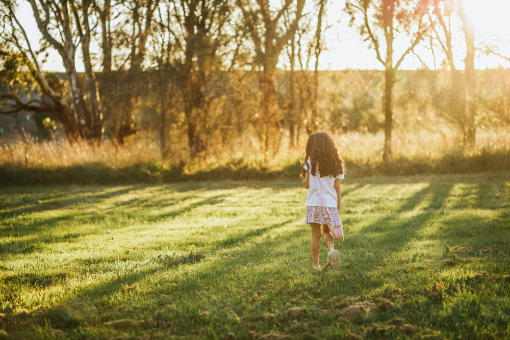 A little girl walking in the park during sunset - Australian Stock Image