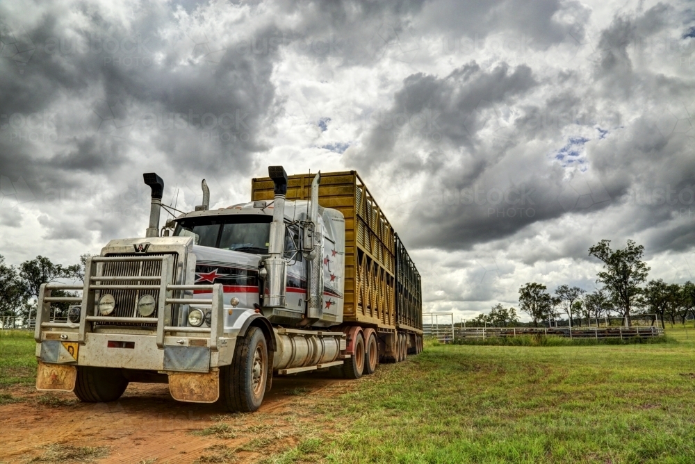 A livestock B-Double semi-trailer truck under a stormy rural sky. - Australian Stock Image
