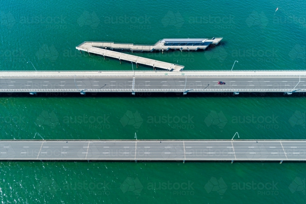 A lone car driving over a bridge above water. - Australian Stock Image