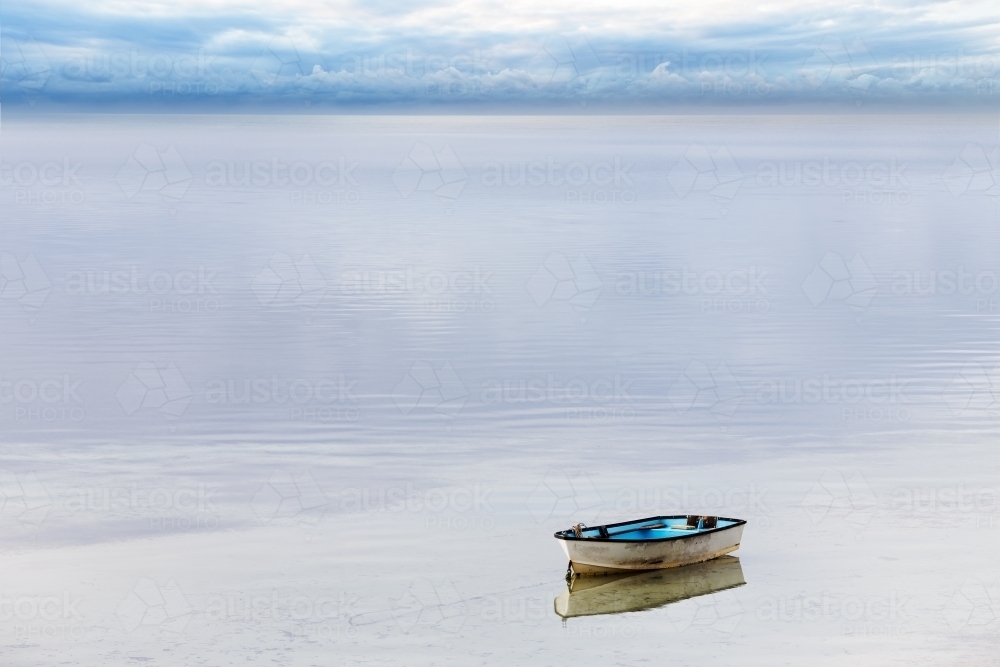 A lone dinghy tied up on still water - Australian Stock Image