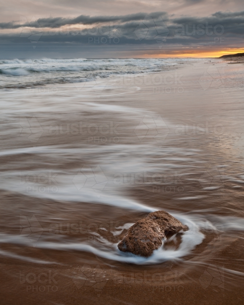 A Lone Rock Being Hit by the Incoming Tide at Thirteenth Beach, Sunrise - Australian Stock Image