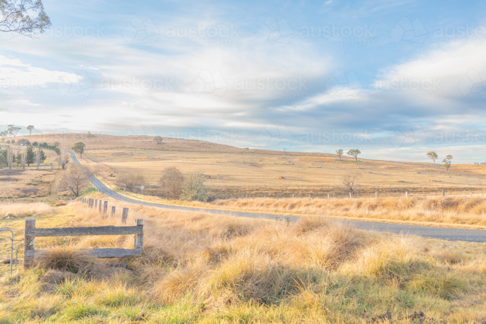 A long country road, lined by winter fields underneath a cloudy sky - Australian Stock Image