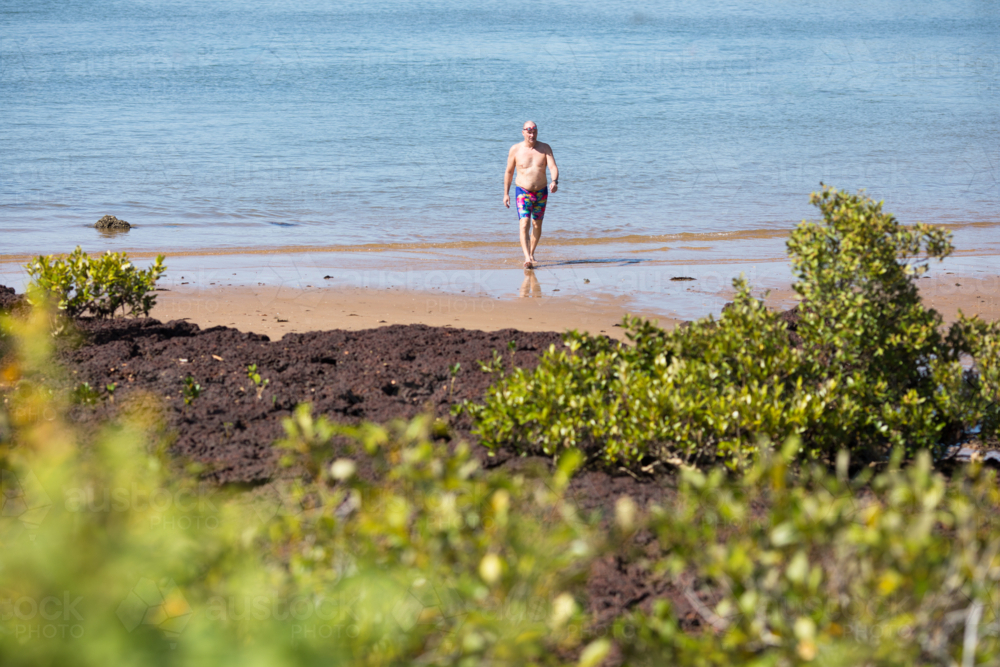 A male middle aged open water swimmer standing in the water at Suttons Beach, Redcliffe - Australian Stock Image