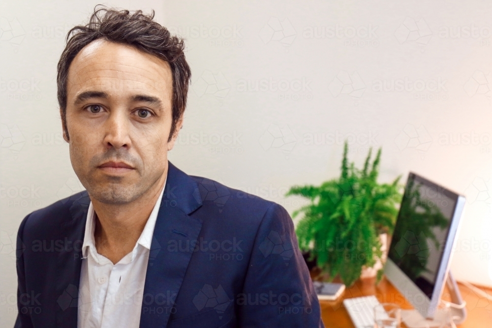 A male office worker standing in front of work desk - Australian Stock Image