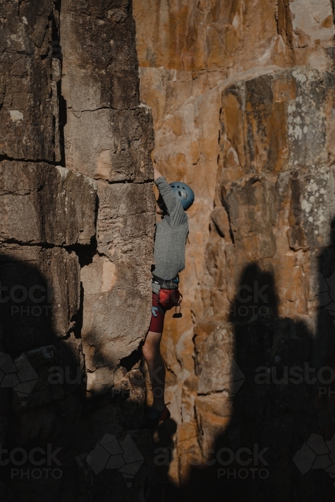 A male rock climber tackling a climbing route at Diamond Beach. - Australian Stock Image