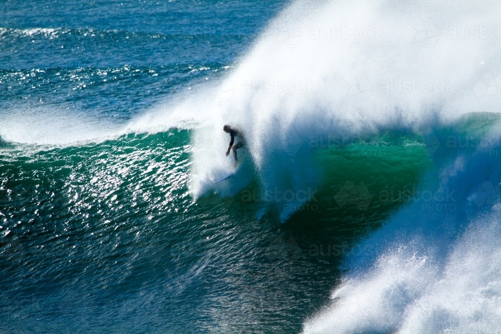 A male surfer in his late twenties surfing a large powerful wave at Sandon Point, NSW - Australian Stock Image