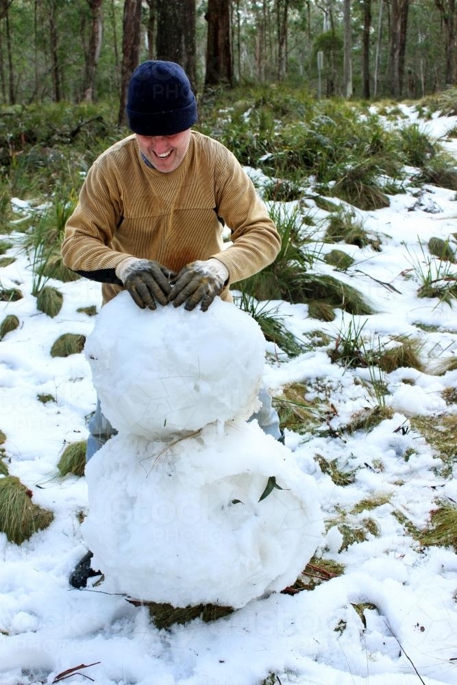 A man building a snowman - Australian Stock Image
