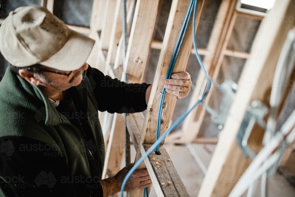 A man cabling in a half built house - Australian Stock Image