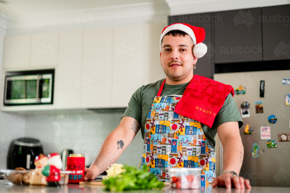 A man in a festive apron in his cheerful kitchen for Christmas - Australian Stock Image