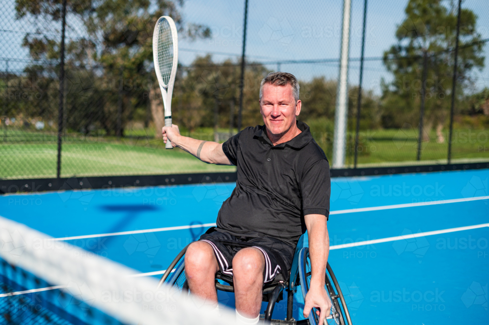 A man in a wheelchair gets ready to smash on a tennis sesh - Australian Stock Image