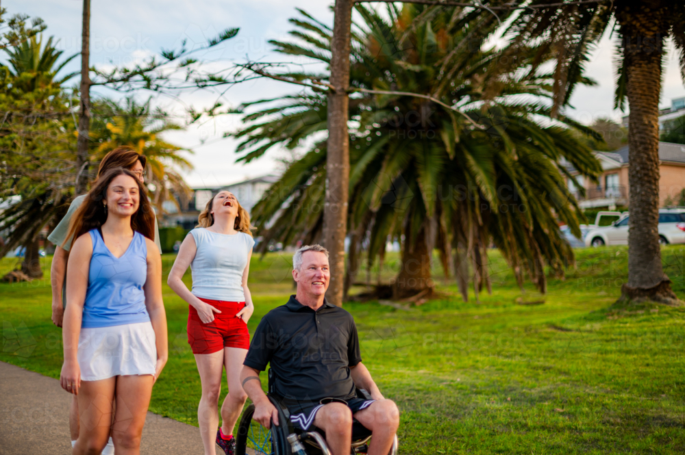 Image of A man in a wheelchair is accompanied by three young adults ...